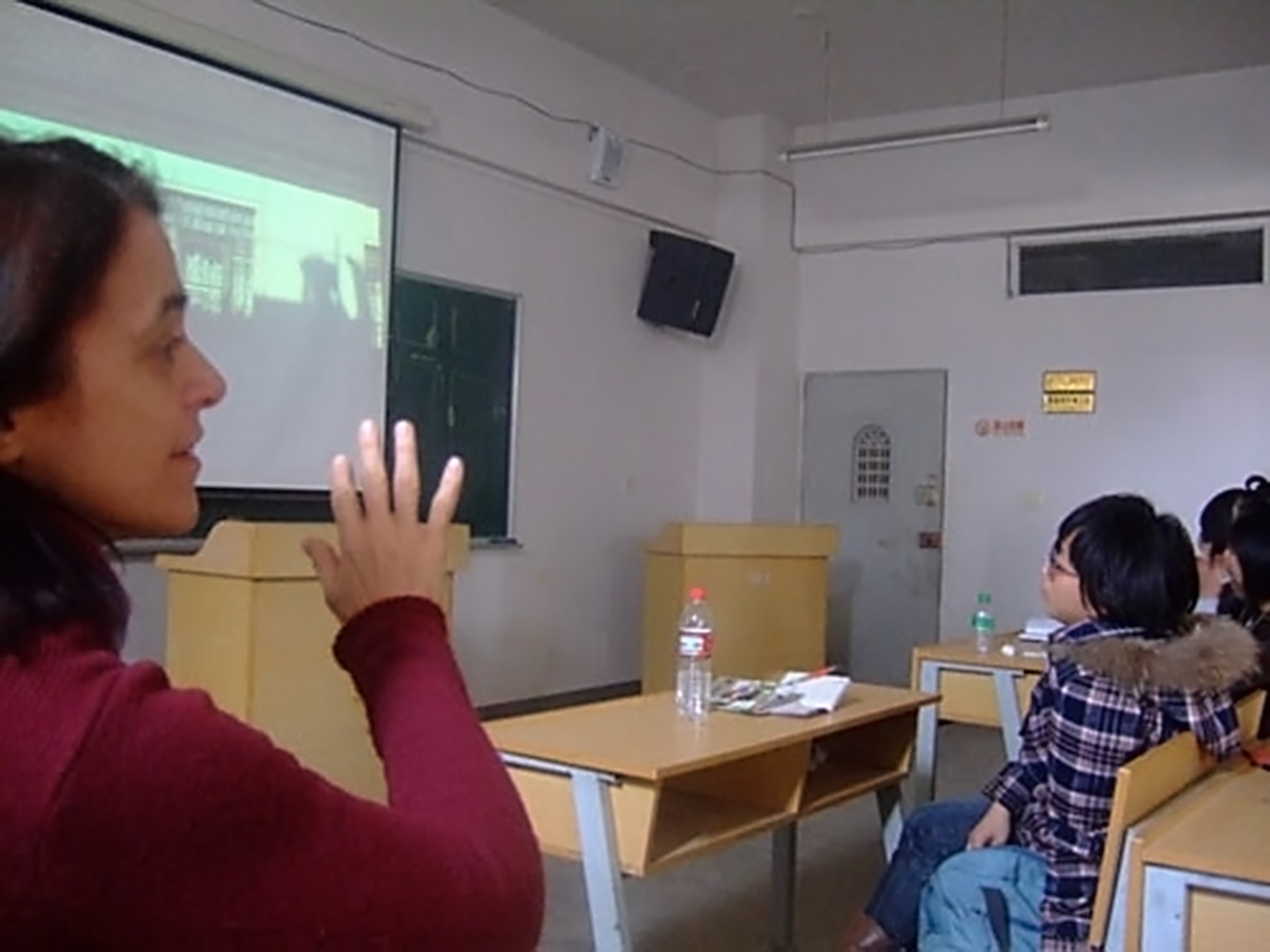 Csáky Marianne a kunmingi Yunnan Art Institute Wenhua College-ban tartott, a nyugati videóművészetet bemutató kurzusán. (A háttérben Szacsvay Pál egyik munkája.)